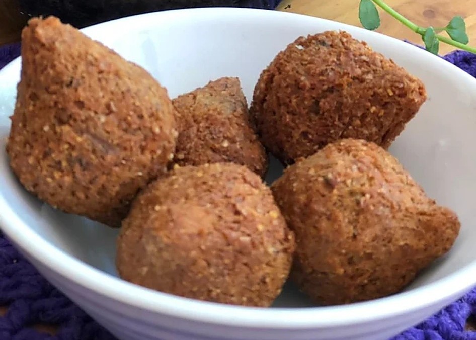 Quibes fritos servidos em tigela branca de louça sobre toalha de crochê roxa
