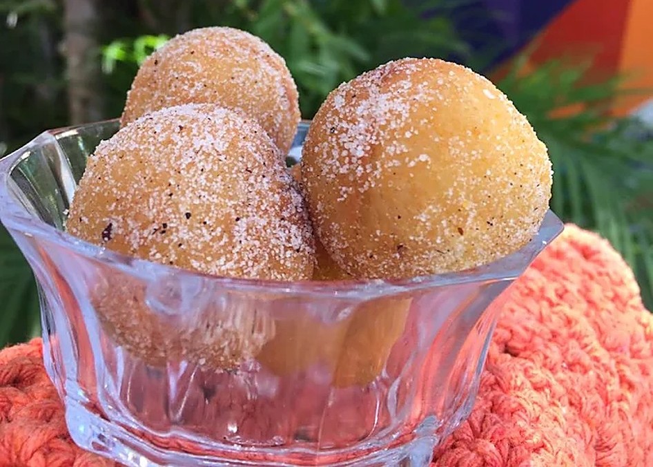 Bolinhos de chuva com açúcar e canela servidos em taça de vidro sobre toalha de crochê coral